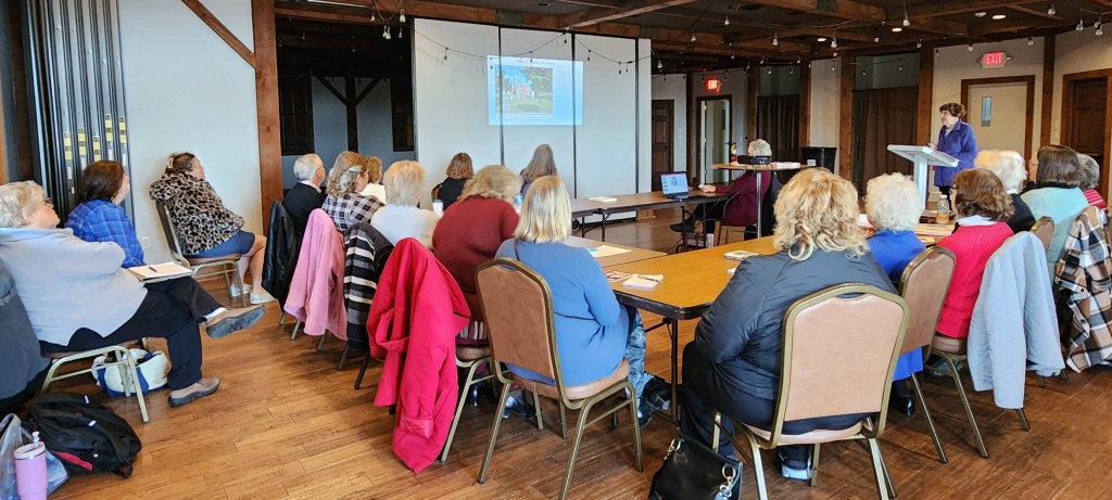 women sitting around tables looking at a screen