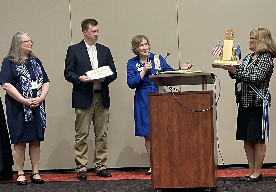 woman presenting a teacher with the Outstanding Teacher of American History award