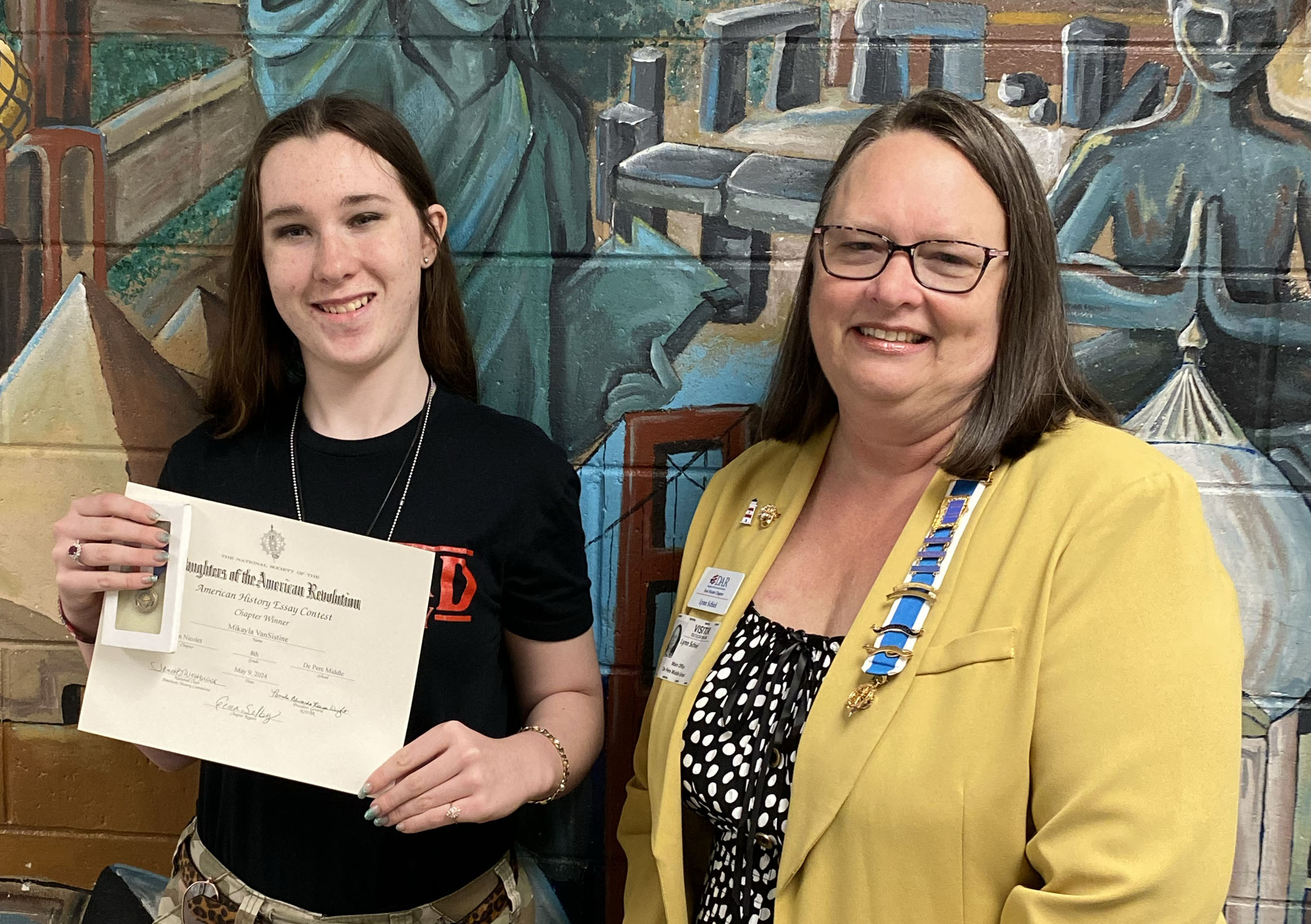 Woman standing by a high school student holding a certificate for an essay contest