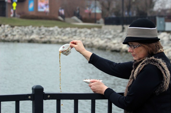 woman pouring tea into the river for the 250th anniversary of the Boston Tea Party