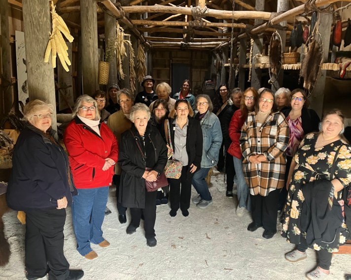 Women standing in a traditional native American long house