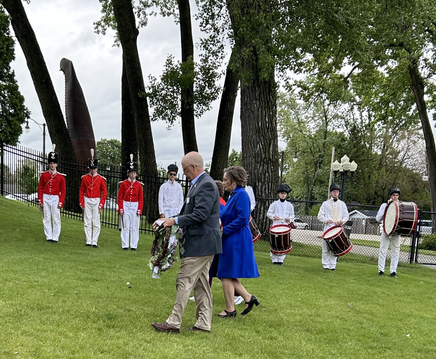 Three people walking with wreaths for a Memorial Day ceremony.